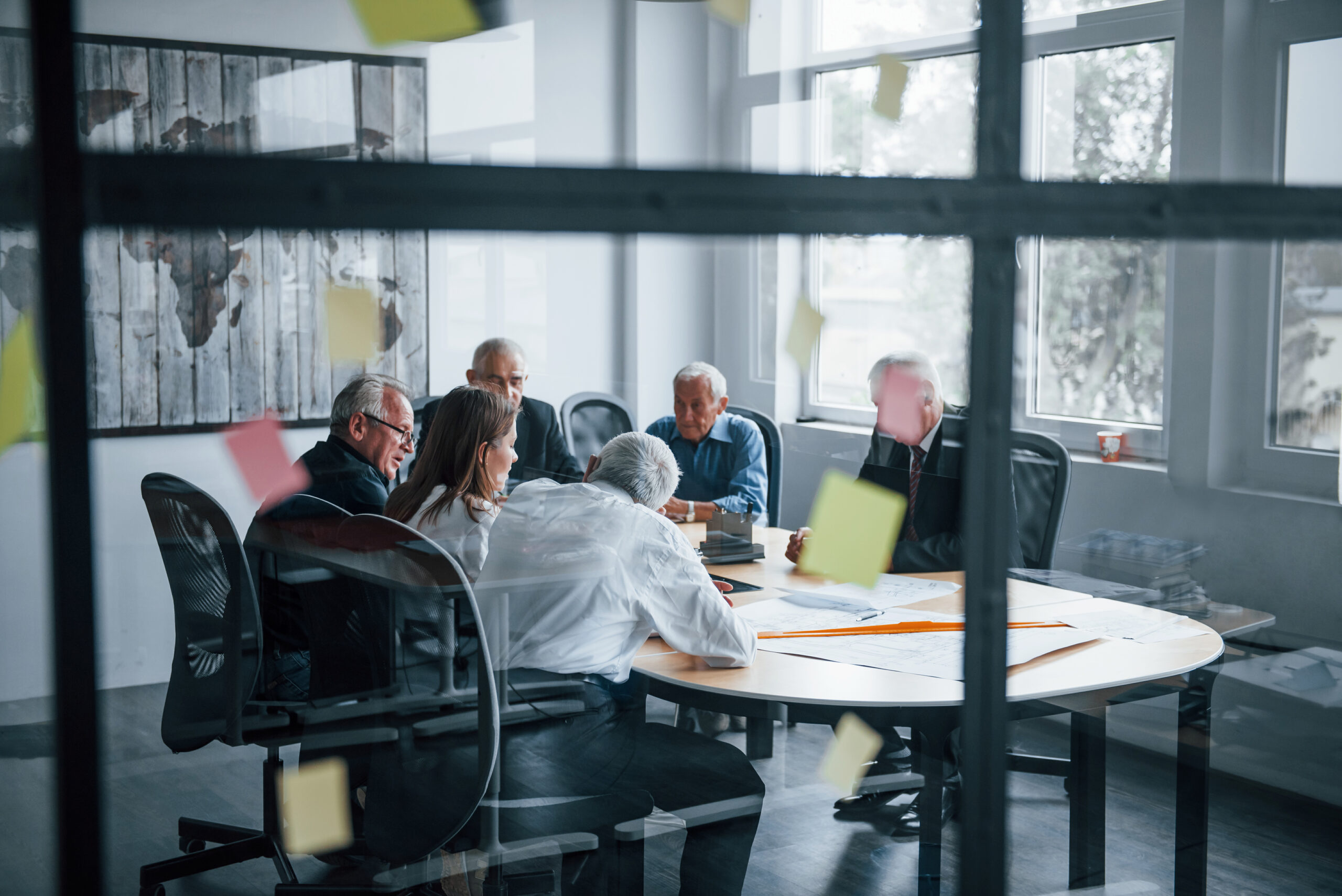 Stickers on the glass. Aged team of elderly businessman architects have a meeting in the office with young woman