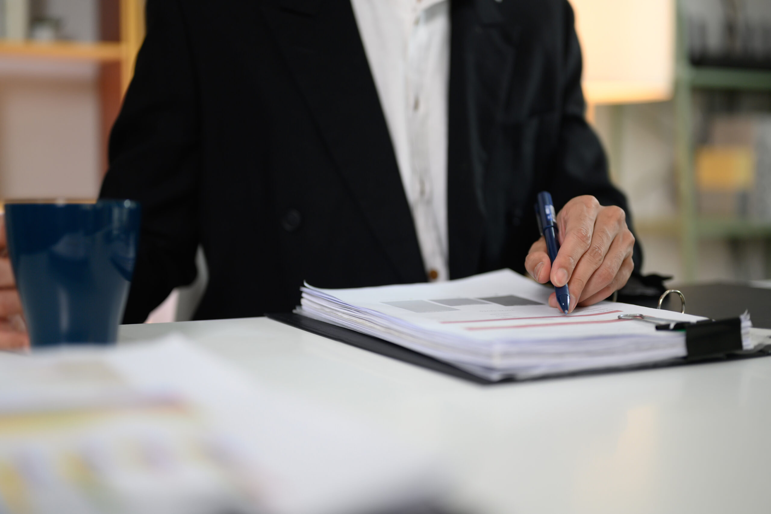 Cropped shot professional investor analyzing graph paper at his workplace