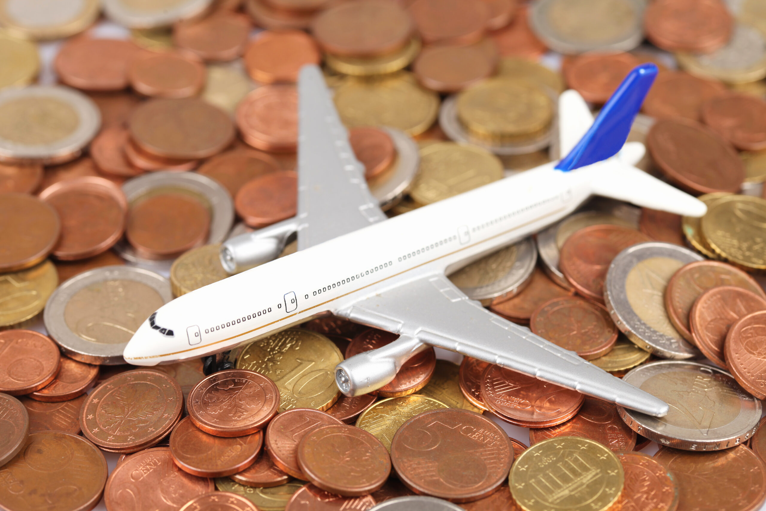 Plane toy on euro coins isolated on a white background - save money for traveling